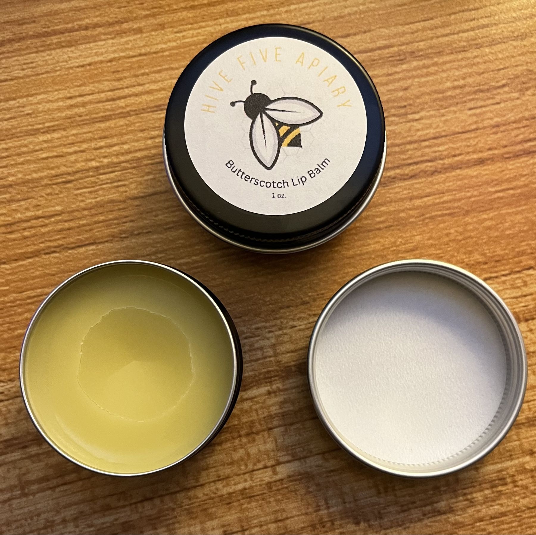 Hive Five Apiary lip balm in its tin, with an open tin beside it